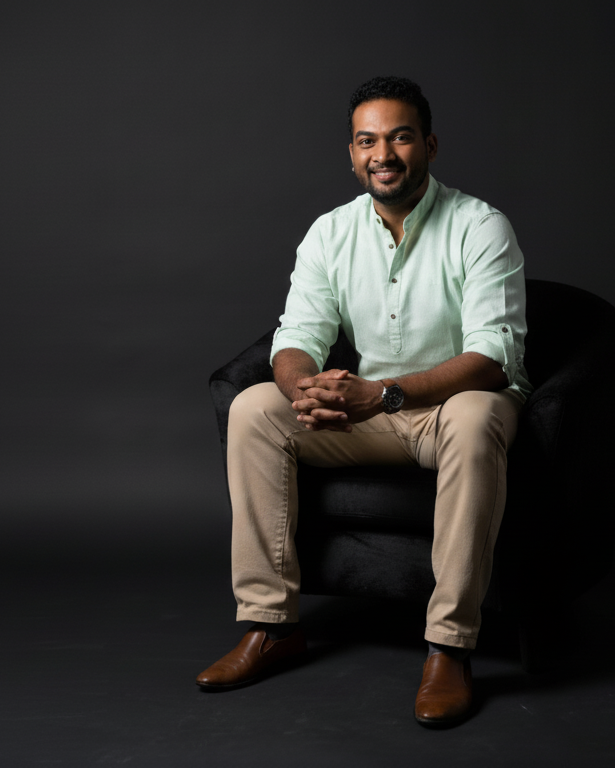 Man sitting on a chair against a dark background. Vishal Kumar, founder of For Humans